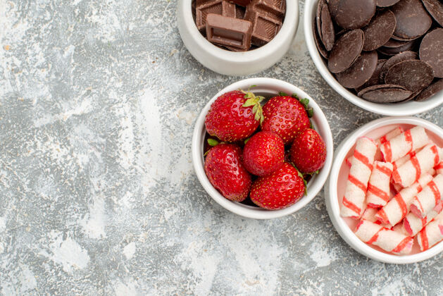 饮食上半部分是在灰白色地面的右上角有草莓 糖果和巧克力的碗健康多汁草莓