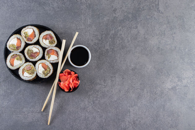 寿司黑色盘子和寿司卷放在石头背景上晚餐Maki美味