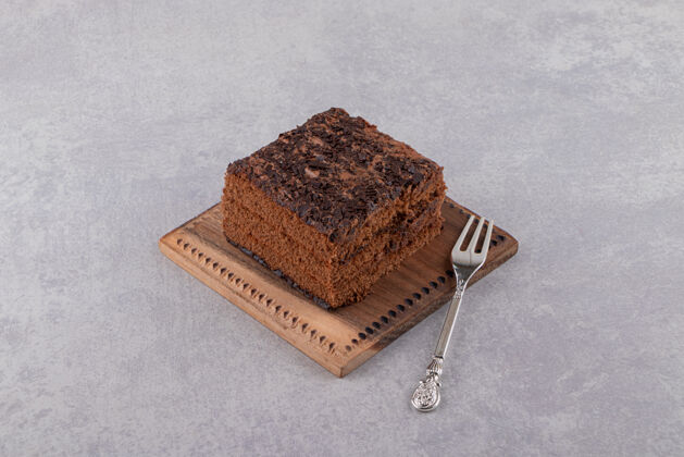 温暖在灰色背景上的木板上的巧克力蛋糕片的特写照片深色配料薯片