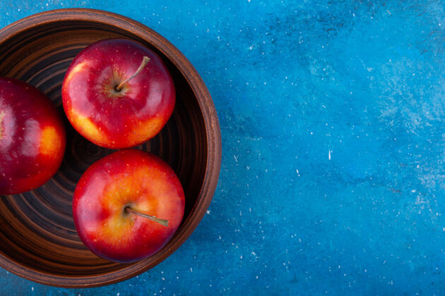 生的美味的红光苹果放在木碗里闪亮成熟可口