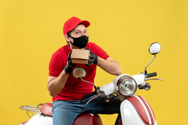 面罩顶视图送货员穿着红色上衣 戴着帽子手套 戴着医用面罩 坐在滑板车上 显示秩序红色车辆摩托车
