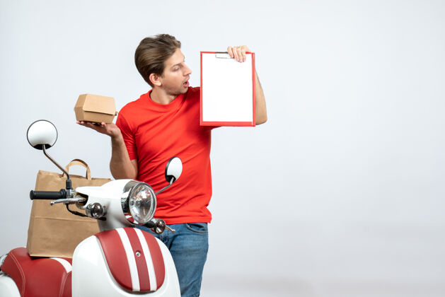 红色顶视图混乱的送货员身穿红色制服 站在滑板车旁 手持订单和文件 背景为白色滑板车站着背景