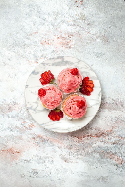 饼干白色表面上有鲜红色草莓的粉色草莓蛋糕俯视图葡萄干盘子茶