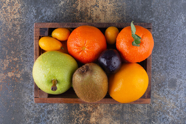 新鲜的放满新鲜水果的木箱放在大理石桌上成熟的柑橘猕猴桃