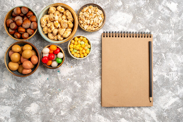 小吃榛子和花生的俯视图 白色表面上有糖果和记事本饮食一餐晚餐
