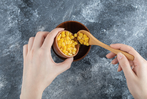 玉米手把爆米花种子放进一个木碗里堆的小的碗