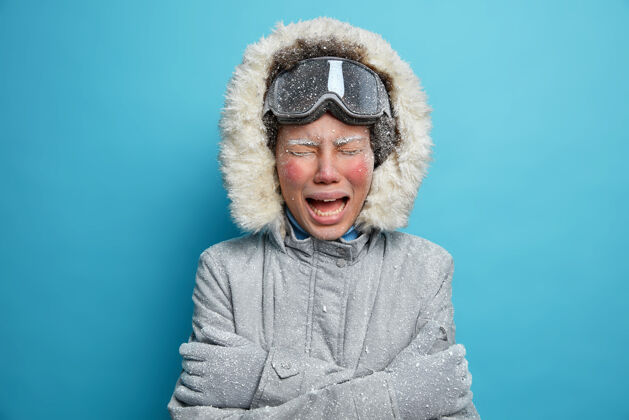 滑雪照片中失望的女人冻红了脸哭泣 感觉很冷 在严寒的冬日里 她花了很多时间在户外 穿着灰色外套 颤抖着 搂着自己娱乐概念可爱失望季节
