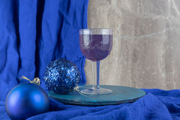 节日蓝色鸡尾酒 蓝色盘子上有闪闪发光的圣诞饰品提神果汁圆球