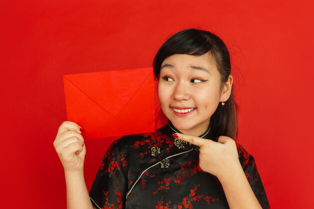 中国2020年中国新年红色背景上的亚洲少女肖像身着传统服装的女模特的特写镜头看起来很开心 并显示红包庆祝 节日 情感服装文化祝福