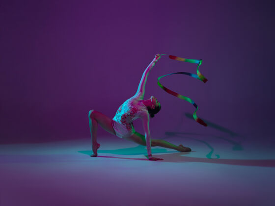 优雅年轻的女运动员 艺术体操艺术家 舞蹈 在紫色的霓虹灯背景下孤立训练美丽的女孩用设备练习优雅的表演灵活表演活动