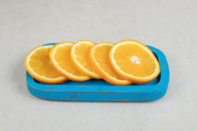 配料新鲜的橘子片放在蓝色盘子里水果营养柑橘