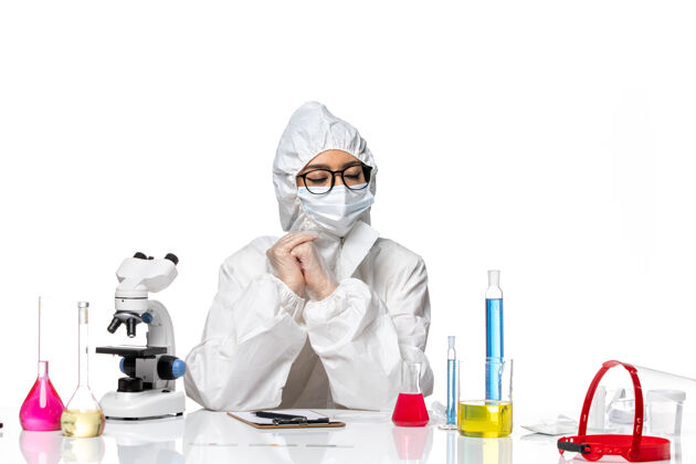 化学前视图穿着特殊防护服的女化学家坐在浅白背景上 解决化学冠状病毒大流行病毒医生坐着
