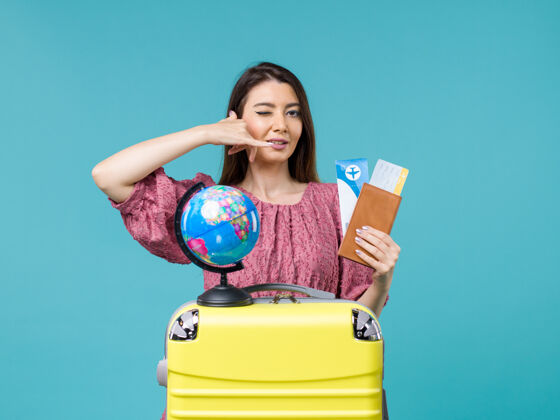 球前视女性在旅行中拿着钱包带着浅蓝色背景的机票女性旅行度假海上旅行旅行运动蓝色