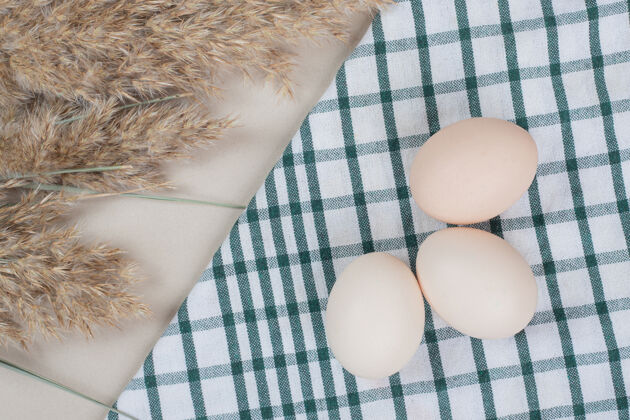 食物桌布上放三个新鲜的鸡蛋未料理的生的家禽