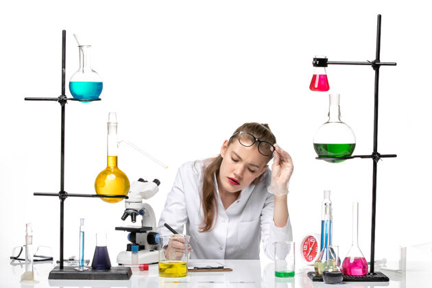 笔记前视图穿着医疗服的女化学家在白色背景上写笔记化学大流行健康病毒正面实验室罐子