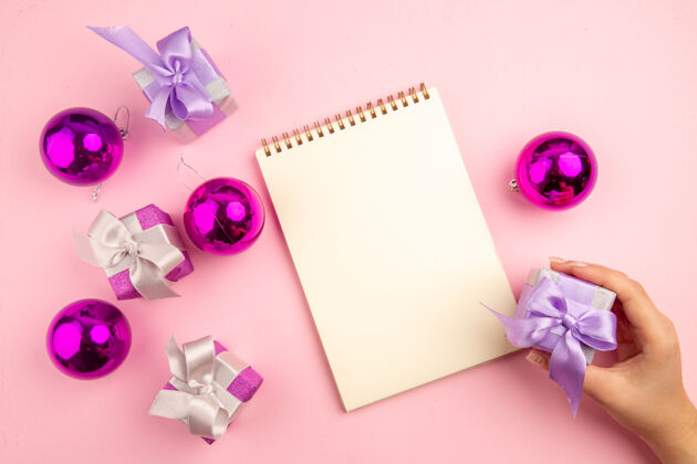 花顶视图的小礼物圣诞树玩具和记事本上的粉红色表面树花框架