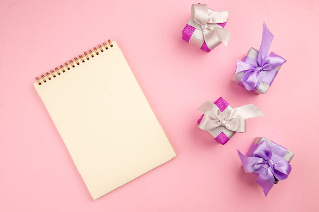 信笺顶视图的小礼物与笔记本上的粉红色表面记事本家庭圣诞节