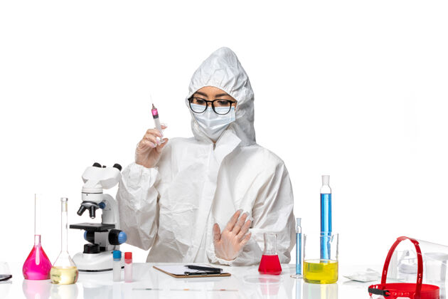 病毒正面图：穿着特殊防护服的女化学家在白色办公桌上注射化学病毒防护视图实验室