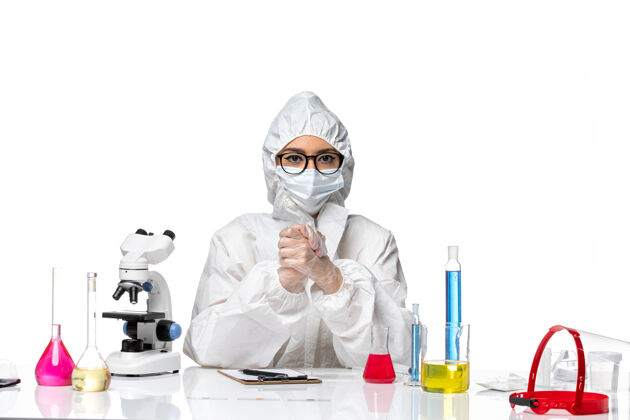 女化学家前视图穿着特殊防护服的女化学家坐在白色背景的化学冠状病毒大流行的解决方案外科医生健康防护