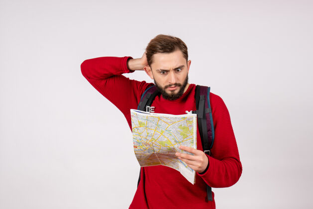 游客正面图年轻男性游客背着背包在白墙上探索地图飞机城市度假情感人文旅游情绪飞机城市