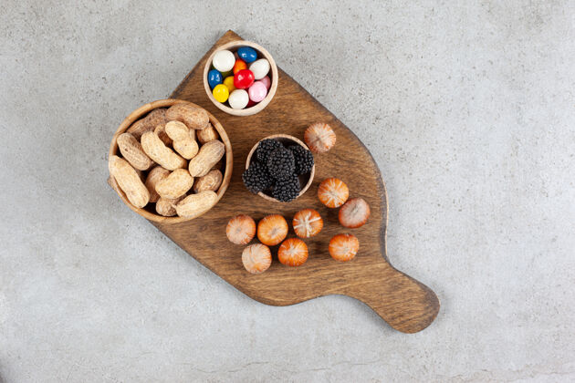碗有坚果和黑莓的木制砧板糖果美味的坚果