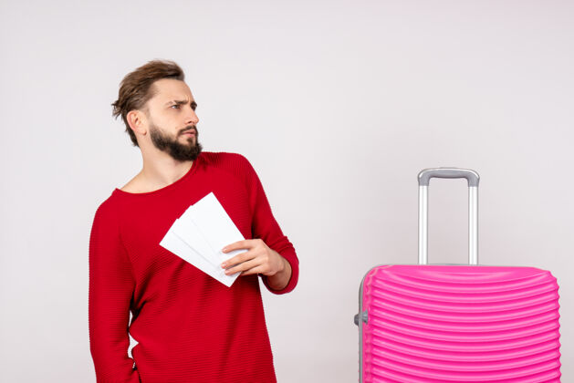 游客正面图：年轻男性 带着粉色包 手持白墙航班彩色旅行旅游度假的机票年轻男性景观航班