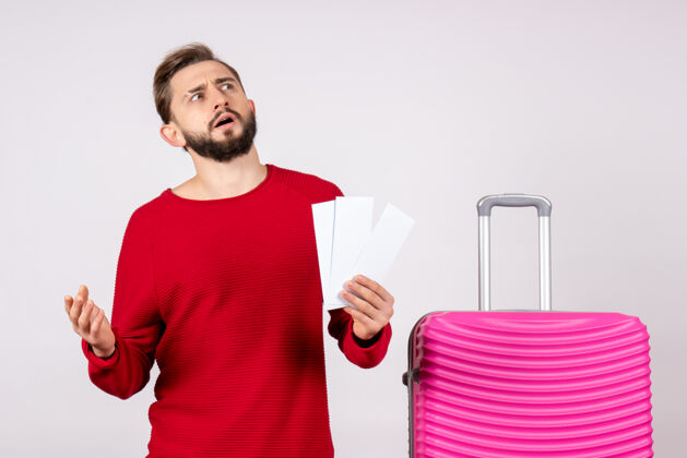 微笑正面图：年轻男性 带着粉色包 手持白墙旅行票 彩色航班 夏季旅游者成人航班游客