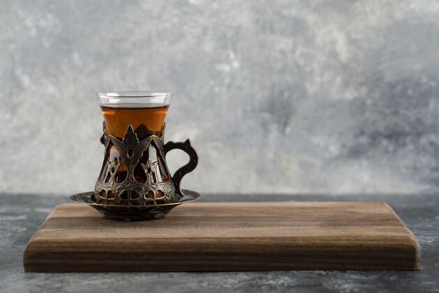 好吃的一杯热茶放在木砧板上杯子草药的茶
