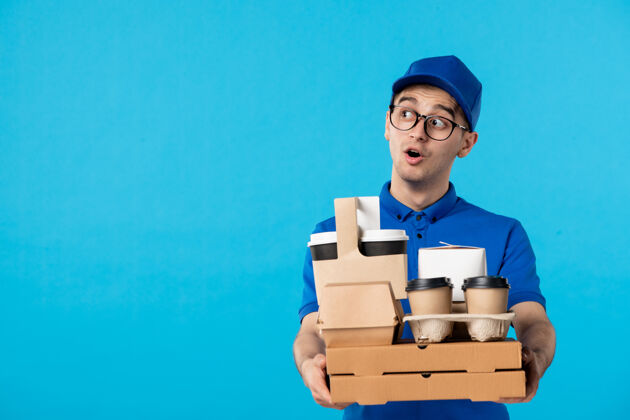 食物正面图男性快递员穿着制服 蓝色的衣服上有食物和咖啡盒子服务男人