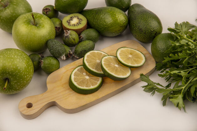 食物新鲜的绿色切片的酸橙在一个木制的厨房板与绿色苹果猕猴桃和鳄梨隔离在一个白色的背景俯视图健康景观苹果