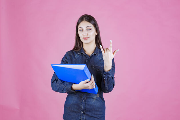 女人女商人拿着一个蓝色的项目文件夹 并显示冷静的手标志自信成人报告