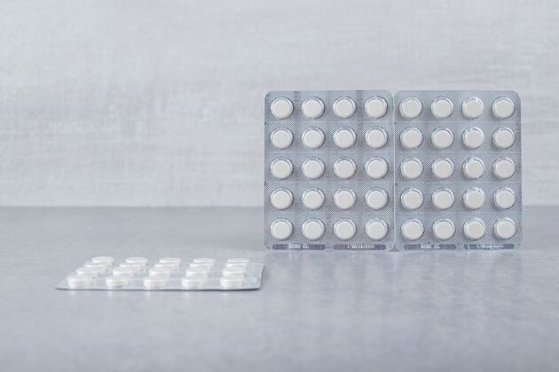药品灰色背景上有很多白色药丸的水泡用药塑料物品