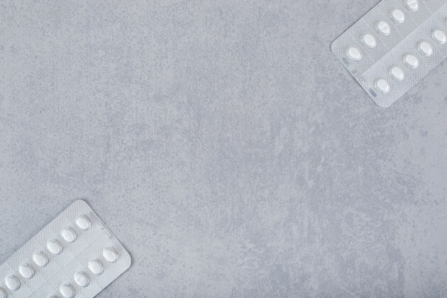 塑料灰色背景上有两个带药片的水泡保健药丸物品