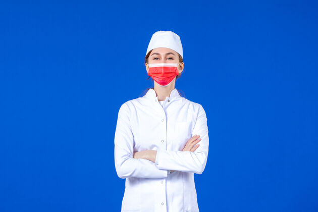医疗正面图身着医疗服的年轻护士 蓝色墙上戴着红色防护面具疾病专业医院