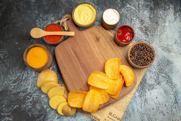 木材上图：自制美味的薯片放在木制砧板上 不同的香料和口味放在灰色的报纸桌上美食食物切割
