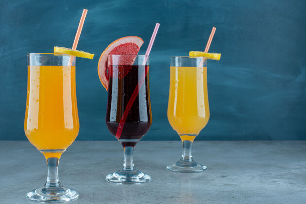 素食三种不同的果汁装在吸管玻璃杯里稻草浆果果汁