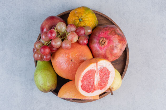 品种新鲜的有机水果放在灰色背景的木碗里自然饮食群体