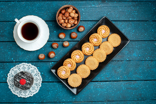 咖啡俯瞰一杯茶 配上坚果和饼干 放在乡村的蓝色桌子上 糖饼干 甜甜的饼干蛋糕坚果顶部