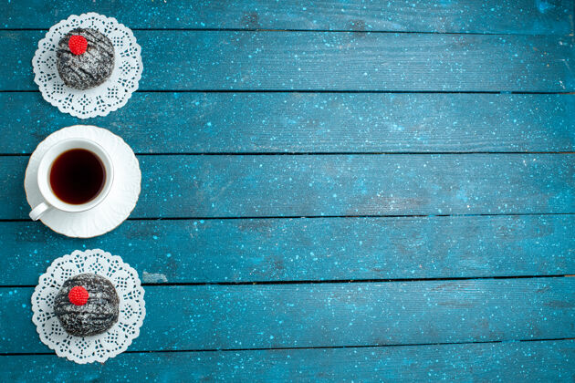 蛋糕俯瞰美味的巧克力球和一杯茶在蓝色的乡村书桌上茶蛋糕饼干饼干甜设备杯子顶部