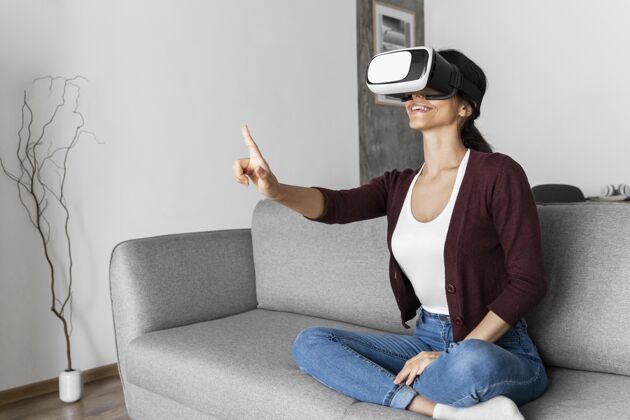 女人用虚拟现实耳机在家里玩得开心的女人女人虚拟现实眼镜虚拟现实眼镜