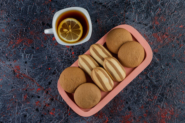 新鲜一杯茶加上甜甜的新鲜饼干放在一块黑板上 一片漆黑茶食物木头