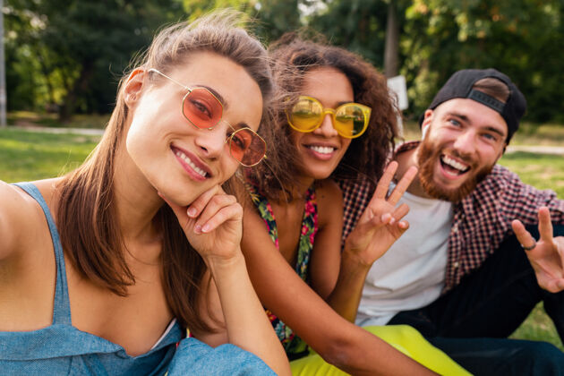团体五彩缤纷时尚快乐的年轻朋友陪伴坐在公园里 男女同乐黄色多样性休闲