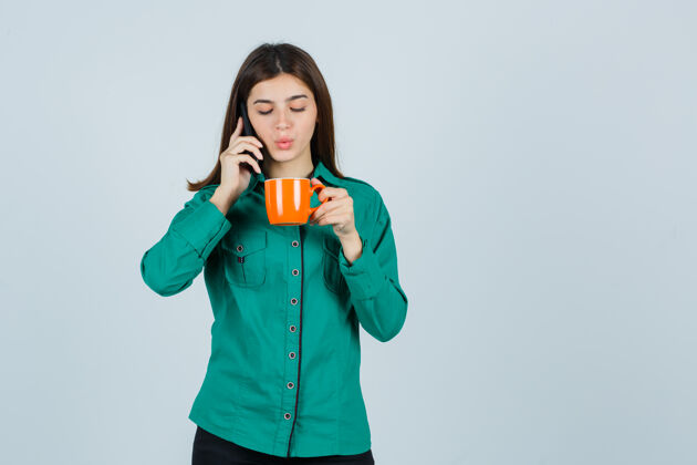 水疗身穿衬衫的年轻女士端着橘黄色的茶杯 讲着手机 神情自信 俯瞰前方电话头发女性
