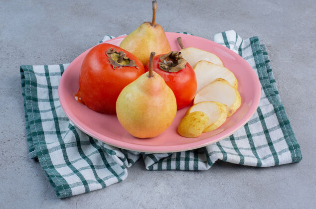 水果一个水果拼盘 在毛巾上放梨和柿子 背景是大理石美味健康拼盘