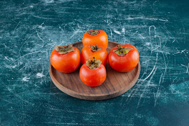 新鲜美味的熟柿子放在木盘上有机水果农业