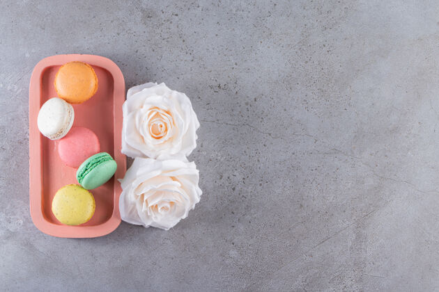 糖果粉红色的甜杏仁蛋糕盘 石头背景上有白玫瑰蛋白酥饼干各种