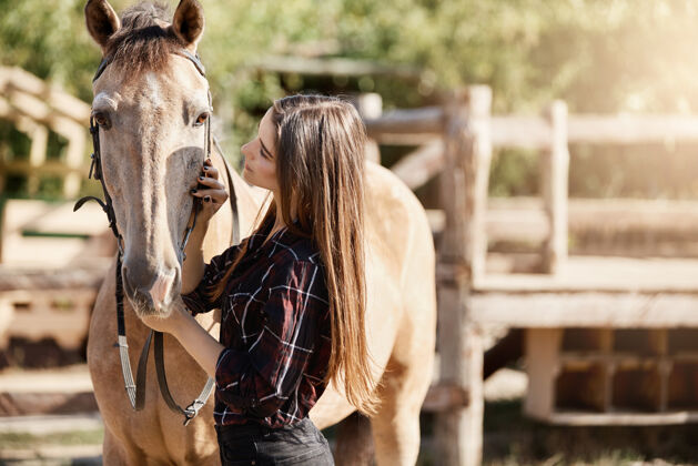 年轻一个年轻的女人在牧场上和她的马交谈很好的职业机会在户外和动物一起工作自然债券国内
