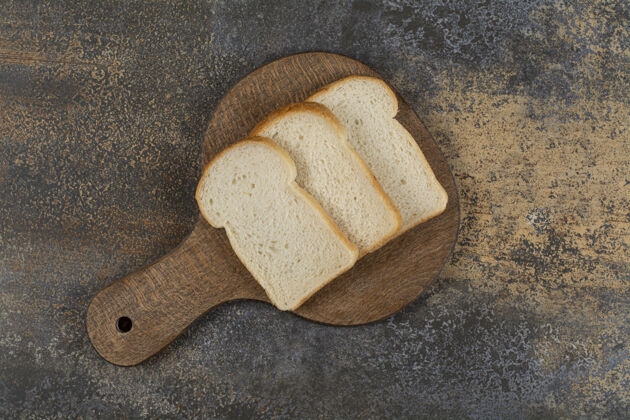 面包在木砧板上放几片白吐司面包新鲜早餐小麦
