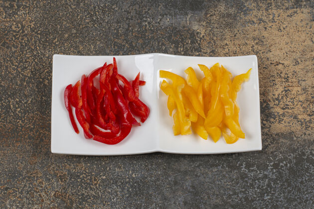 胡椒把红黄辣椒片放在白盘子里小吃有机蔬菜