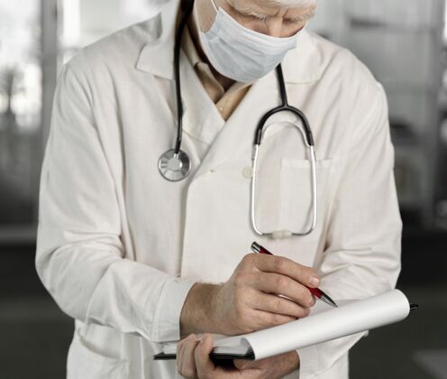 诊所戴着医用面罩的医生在检查他的笔记健康面膜实验室